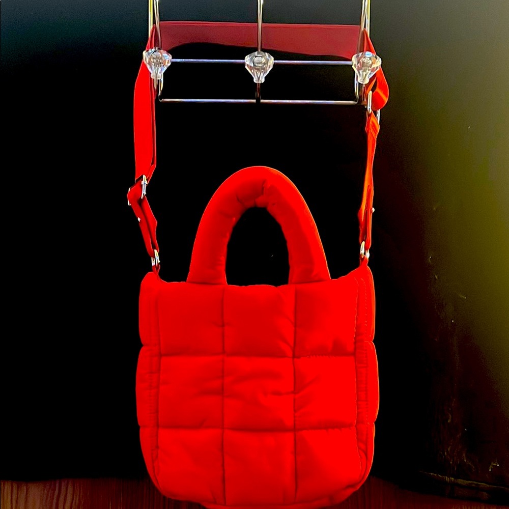 Red, adjustable hand bag, with quilted stitching.
